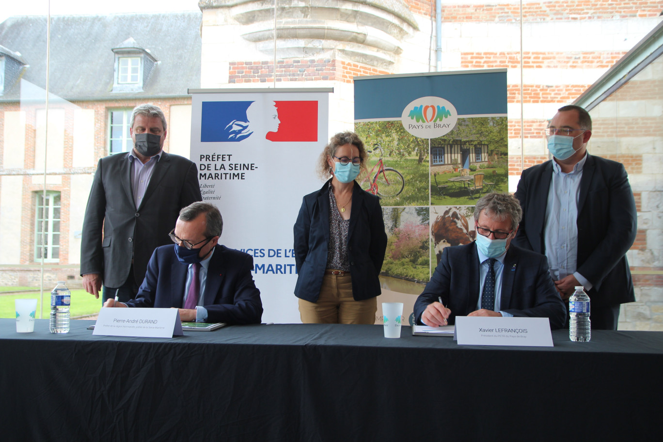 De g. à dr. : Debouts, les présidents d’intercommunalités Eric Picard (Quatre Rivières), Armelle Biloquet (Londinières) et Nicolas Bertrand (Bray-Eawy), assistent à la signature du CRTE par Pierre-André Durant et Xavier Lefrançois. (© Aletheia Press / Benoit Delabre) 