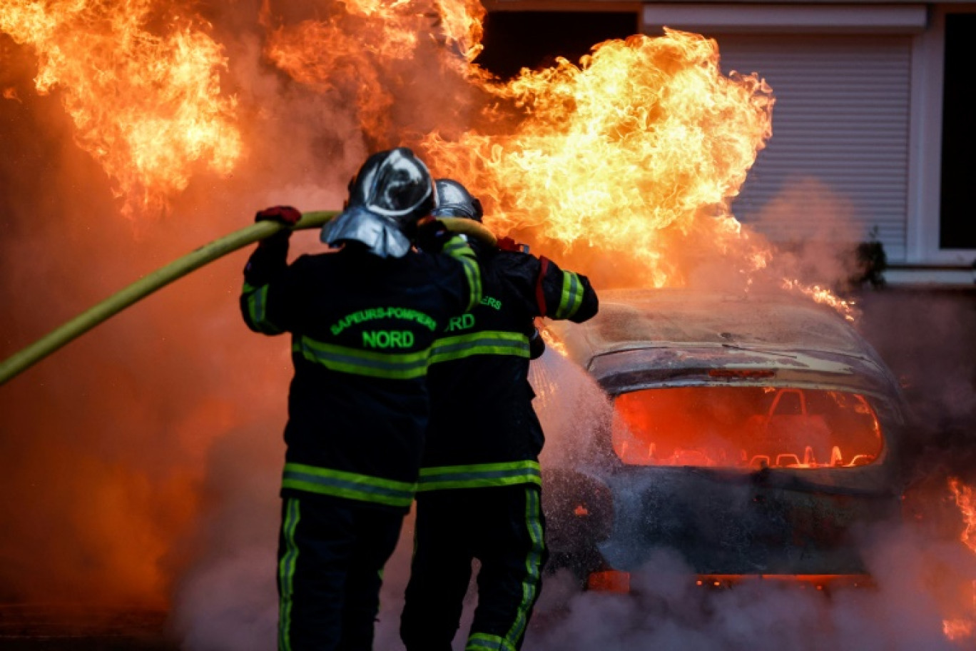 Les pompiers interviennent sur une voiture incendiée pendant des violences à Lille, le 29 juin 2023 © KENZO TRIBOUILLARD