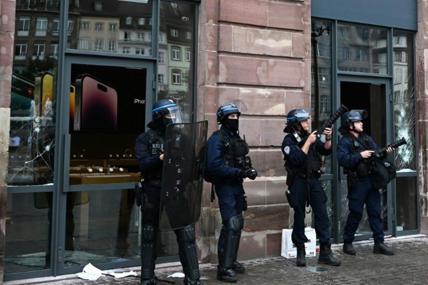 Des policiers gardent l'entrée d'un magasin Apple vandalisé, le 30 juin 2023 à Strasbourg © PATRICK HERTZOG