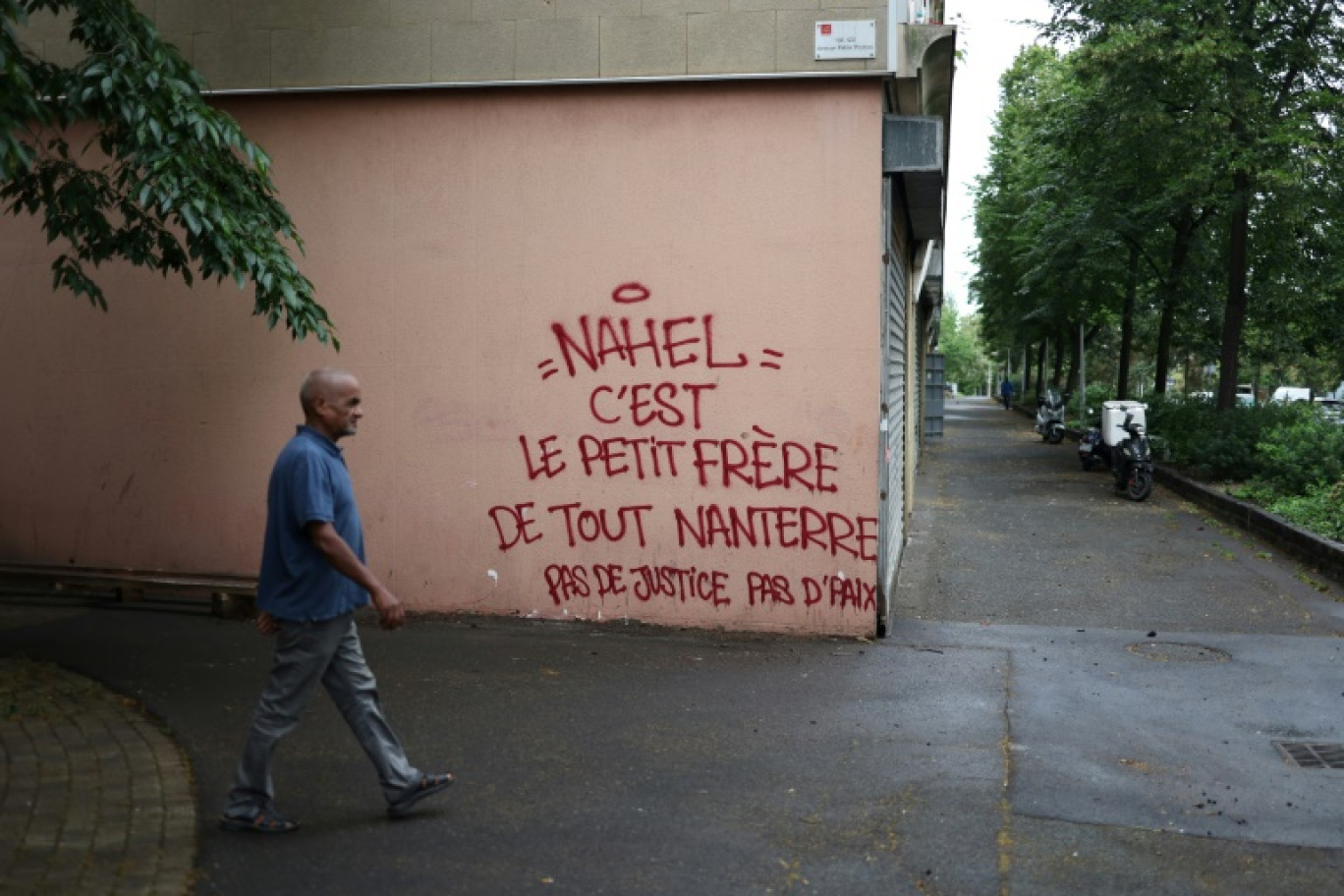 Un piéton passe près d'un graffiti en hommage à Nahel, tué par un policier, dans le quartier populaire Pablo Picasso à Nanterre, le 1er juillet 2023 © CHARLY TRIBALLEAU