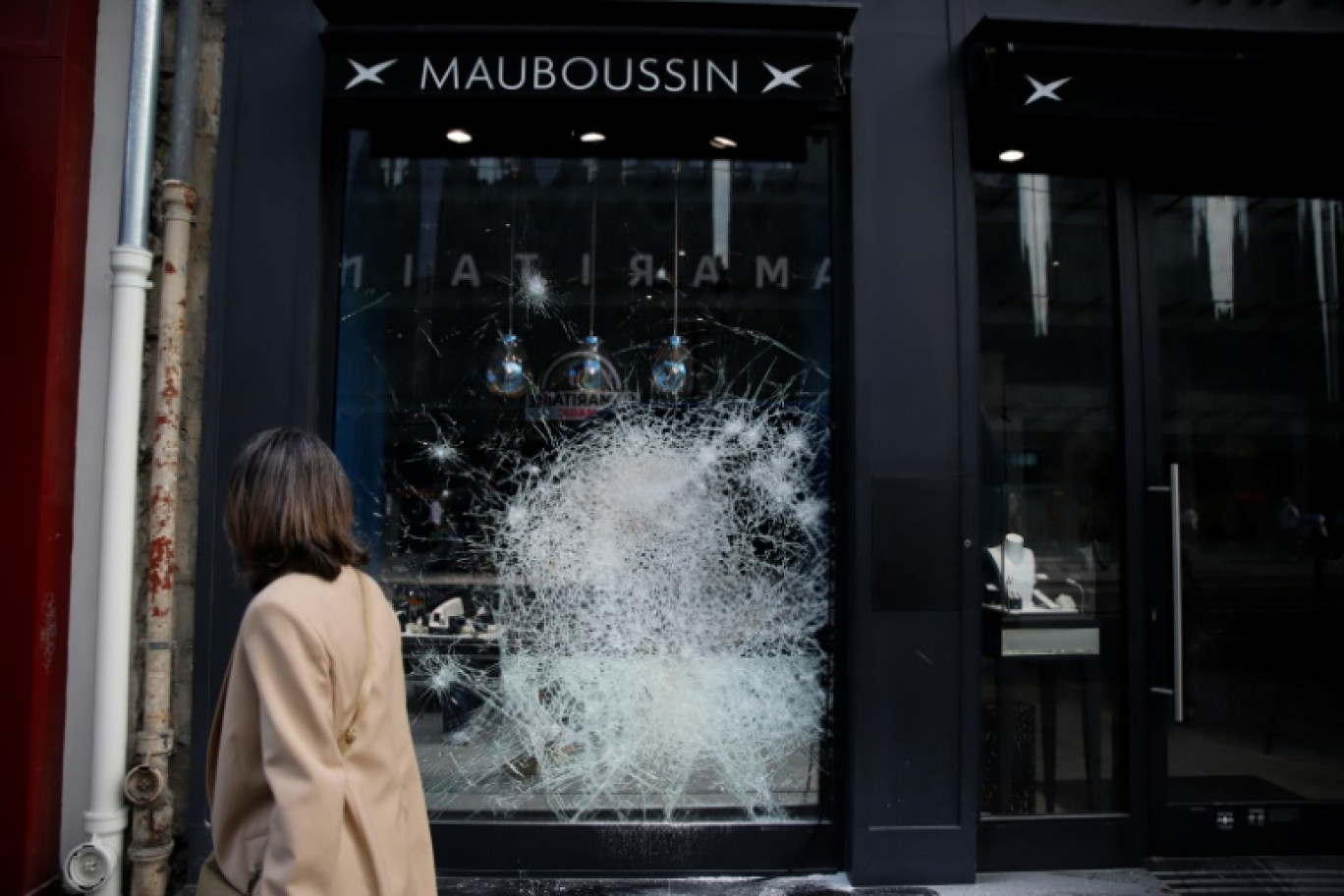 Une femme passe devant la vitrine d'un magasin un magasin endommagé après des émeutes, le 27 juin 2023 à Paris © -