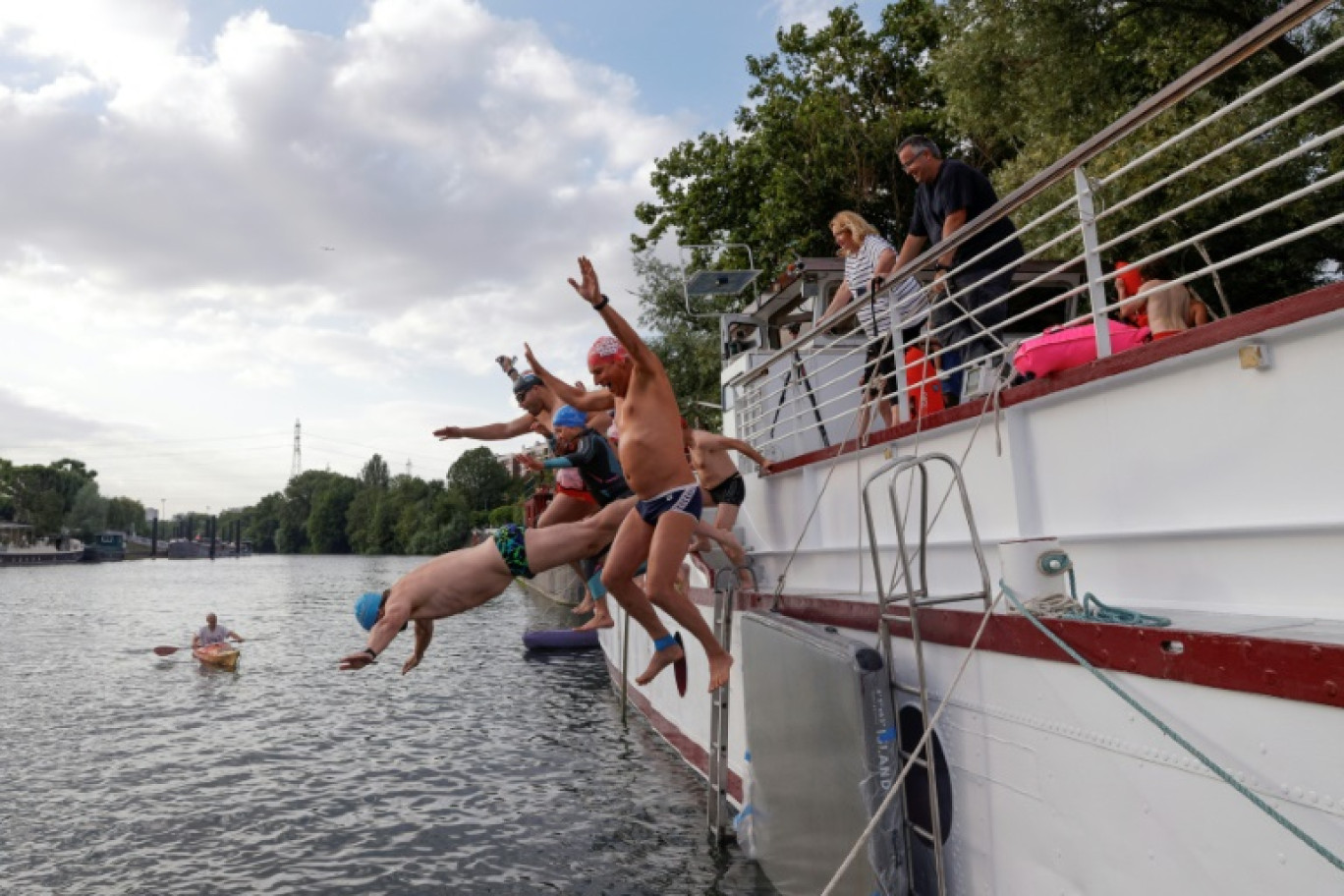 Un groupe de nageurs saute dans la Seine depuis une péniche à l'Ile-Saint-Denis, en Seine-Saint-Denis, le 2 juillet 2023 © Geoffroy Van der Hasselt