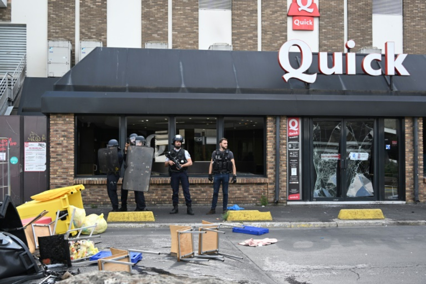 Des policiers devant un fast-food Quick aux vitres brisées pendant des émeutes, le 30 juin 2023 à Rosny-sous-Bois, en Seine-Saint-Denis © Bertrand GUAY