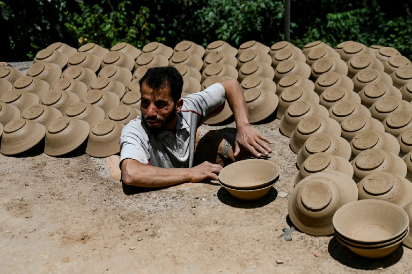 Un potier récupère des bols en argile séchés au soleil pour les faire cuire dans son four, le 3 juillet 2023 dans le district d'Istalif, près de Kaboul, en Afghanistan © Wakil Kohsar