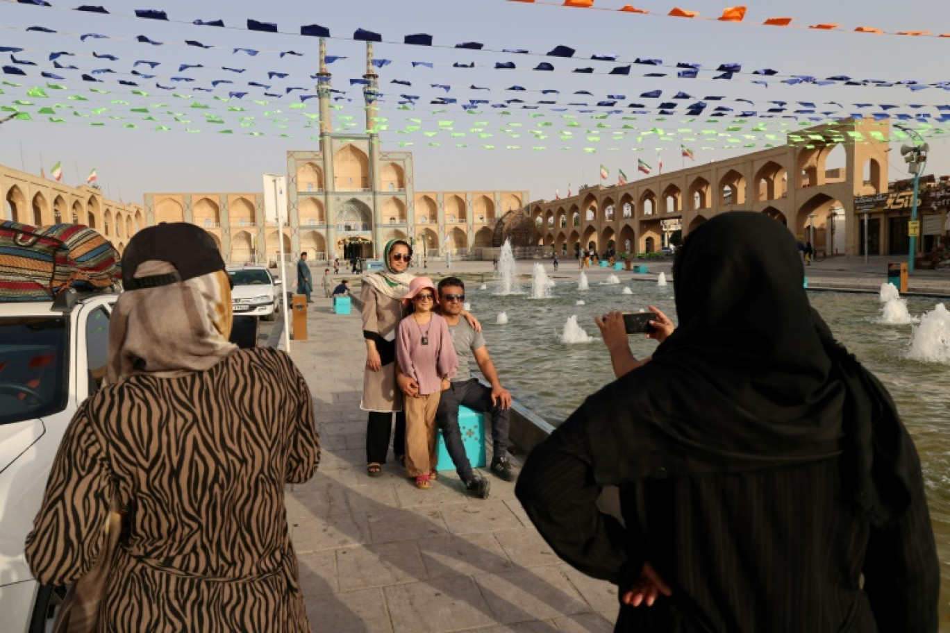 Des visiteurs se font photographier devant la mosquée Amir Chakhmaq, le 4 juillet 2023 à Yazd, en Iran © ATTA KENARE