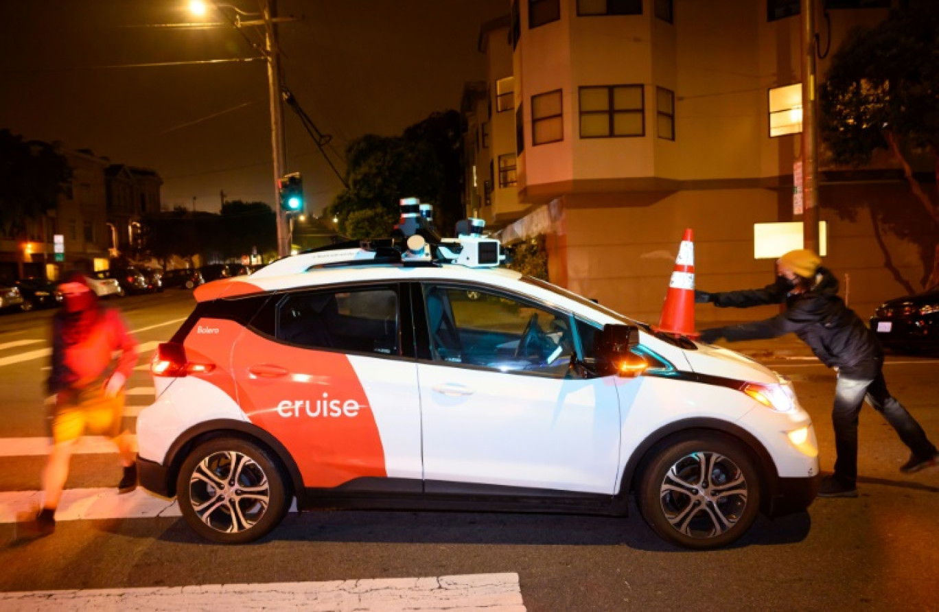 Des membres du collectif "Safe Street Rebel" déposent un cône de chantier sur une voiture autonome pour l'immobiliser, le 11 juillet 2023 à San Francisco © Josh Edelson