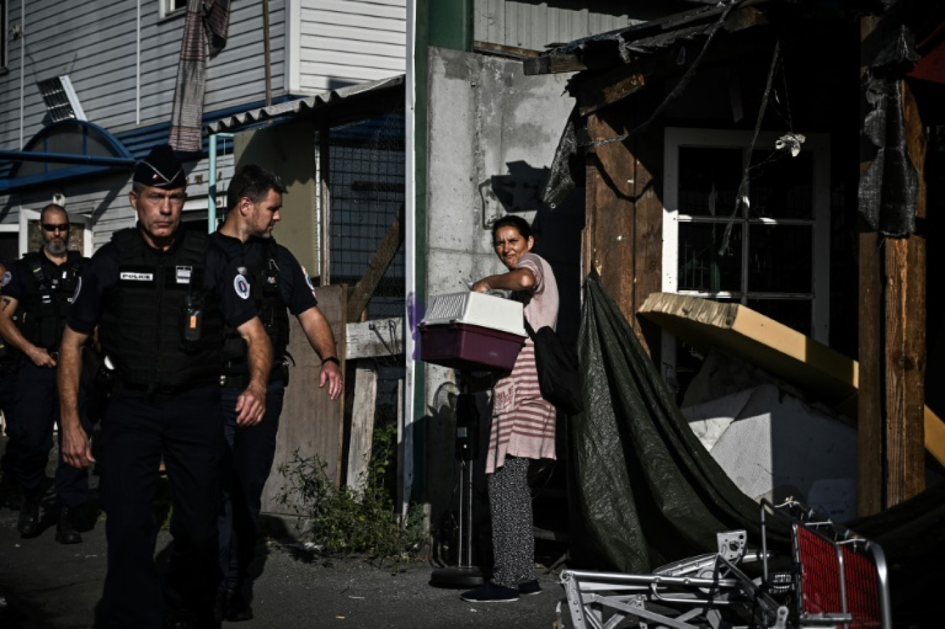 Des policiers passent devant une occupante du principal bidonville de Bordeaux, pendant une opération d'évacuation, le 19 juillet 2023 © PHILIPPE LOPEZ