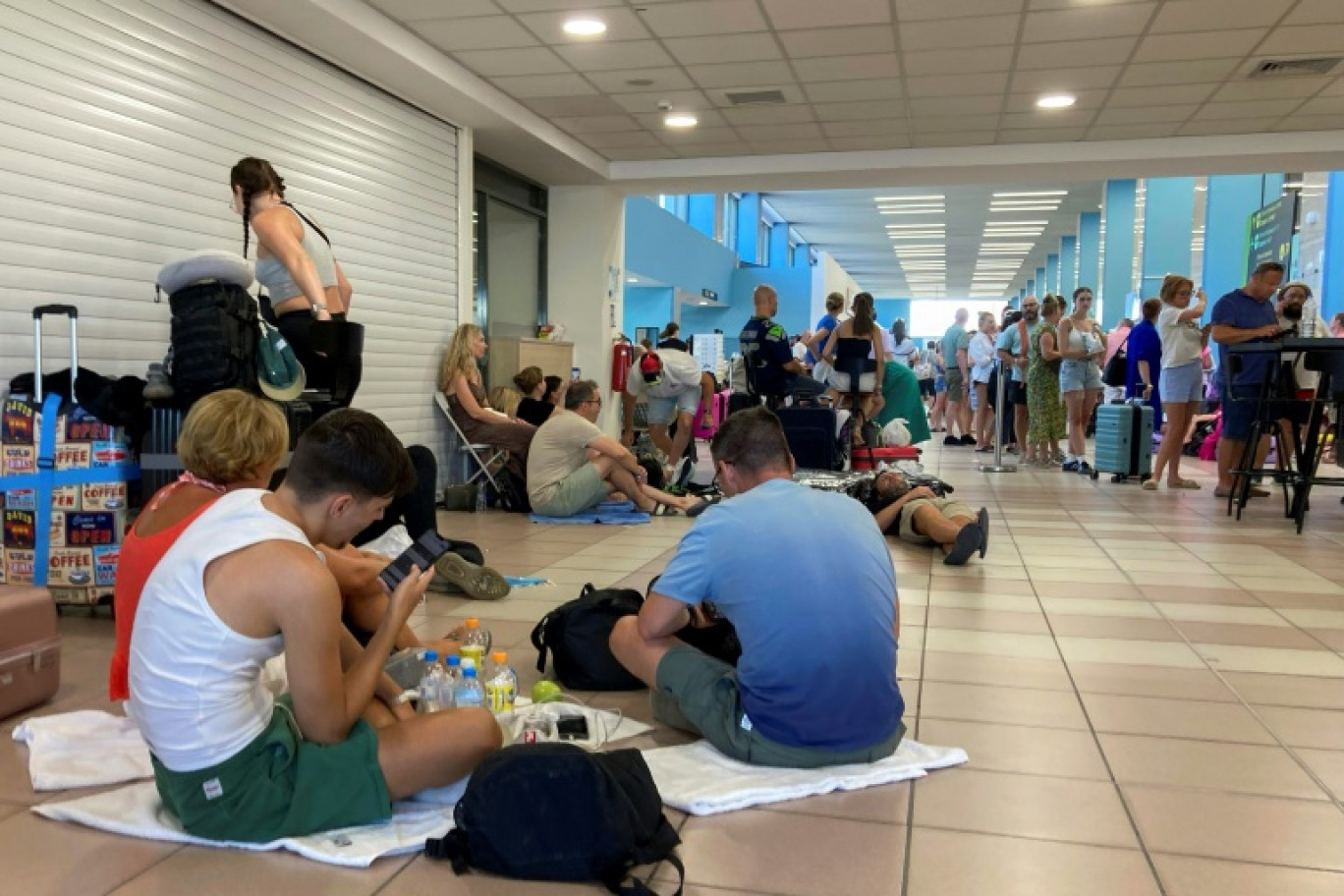 Des touristes attendent leur évacuation dans le hall des départs de l'aéroport international de Rhodes, en Grèce, le 23 juillet 2023 © Will VASSILOPOULOS