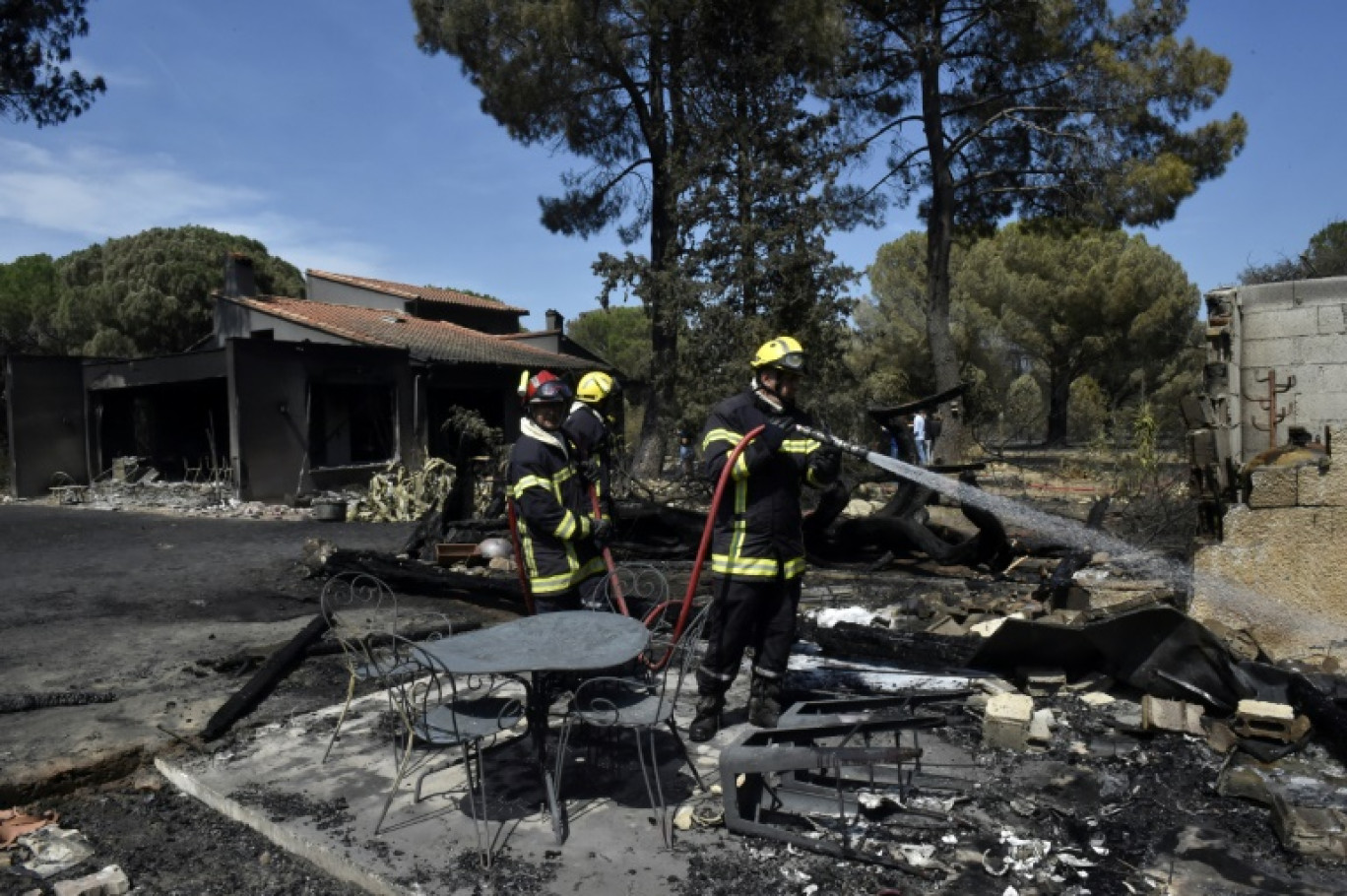 Un pompier arrose les décombres d'une maison détruite par un incendie, le 15 août 2023 à Saint-André, près d'Argelès-sur-Mer, dans les Pyrénées-Orientales © RAYMOND ROIG