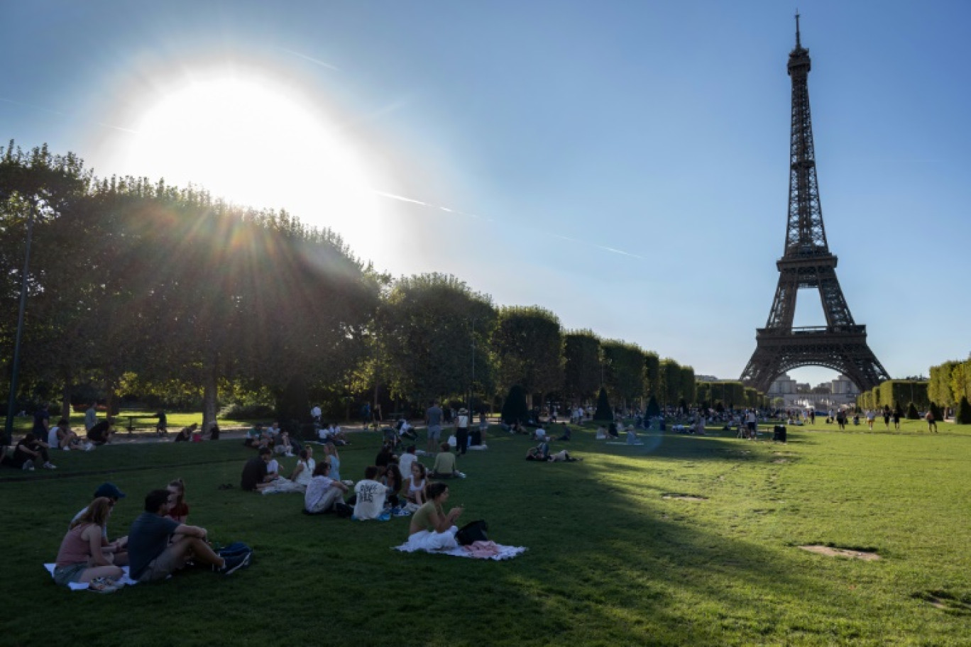 Des personnes profitent de l'ombre sur les pelouses du Champs de Mars, devant la Tour Eiffel, à Paris, pendant un épisode de canicule, le 21 août 2023 © BERTRAND GUAY