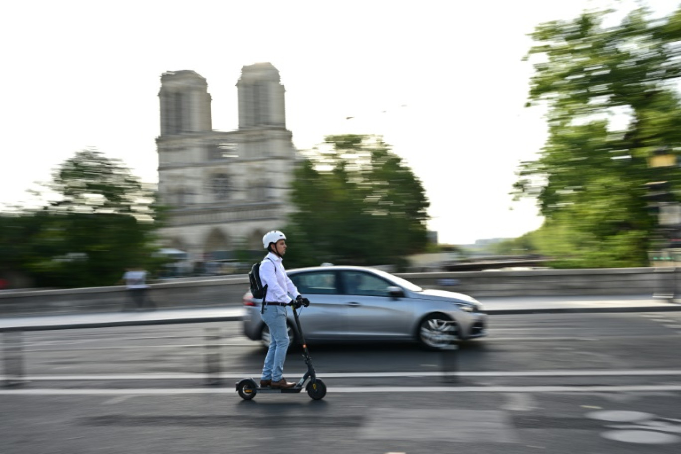 Un homme passe en trottinette électrique devant la cathédrale Notre-Dame de Paris le 23 août 2023 © MIGUEL MEDINA