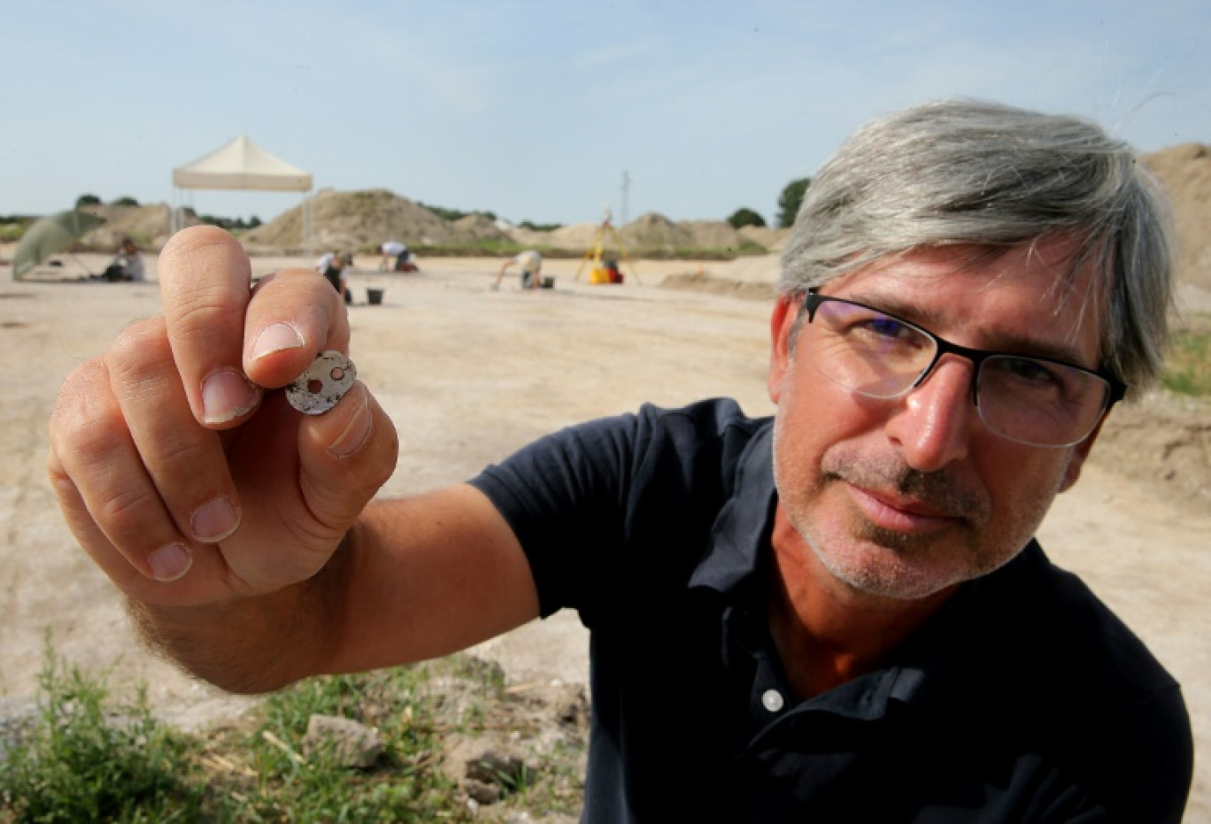 Rémi Martineau, chercheur au CNRS, montre un élément ovale en nacre de moule d'eau douce découvert sur le site d'un village du Néolithique récent au Val-des-Marais, le 23 août 2023 dans le sud de la Marne © FRANCOIS NASCIMBENI