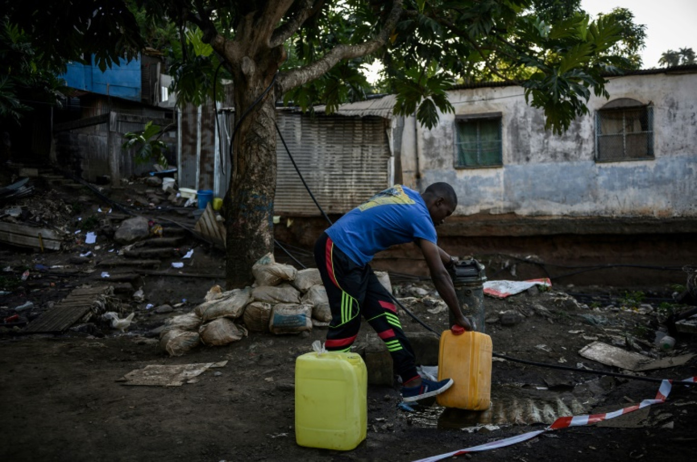 Le 23 mai 2023, à Koungou, un habitant remplit des bidons d'eau © PHILIPPE LOPEZ