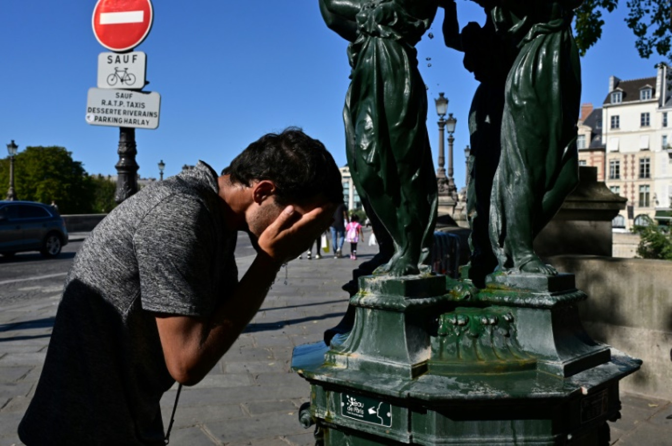 Un homme se rafraichit dans une fontaine publique à Paris le 21 août 2023 © Miguel MEDINA