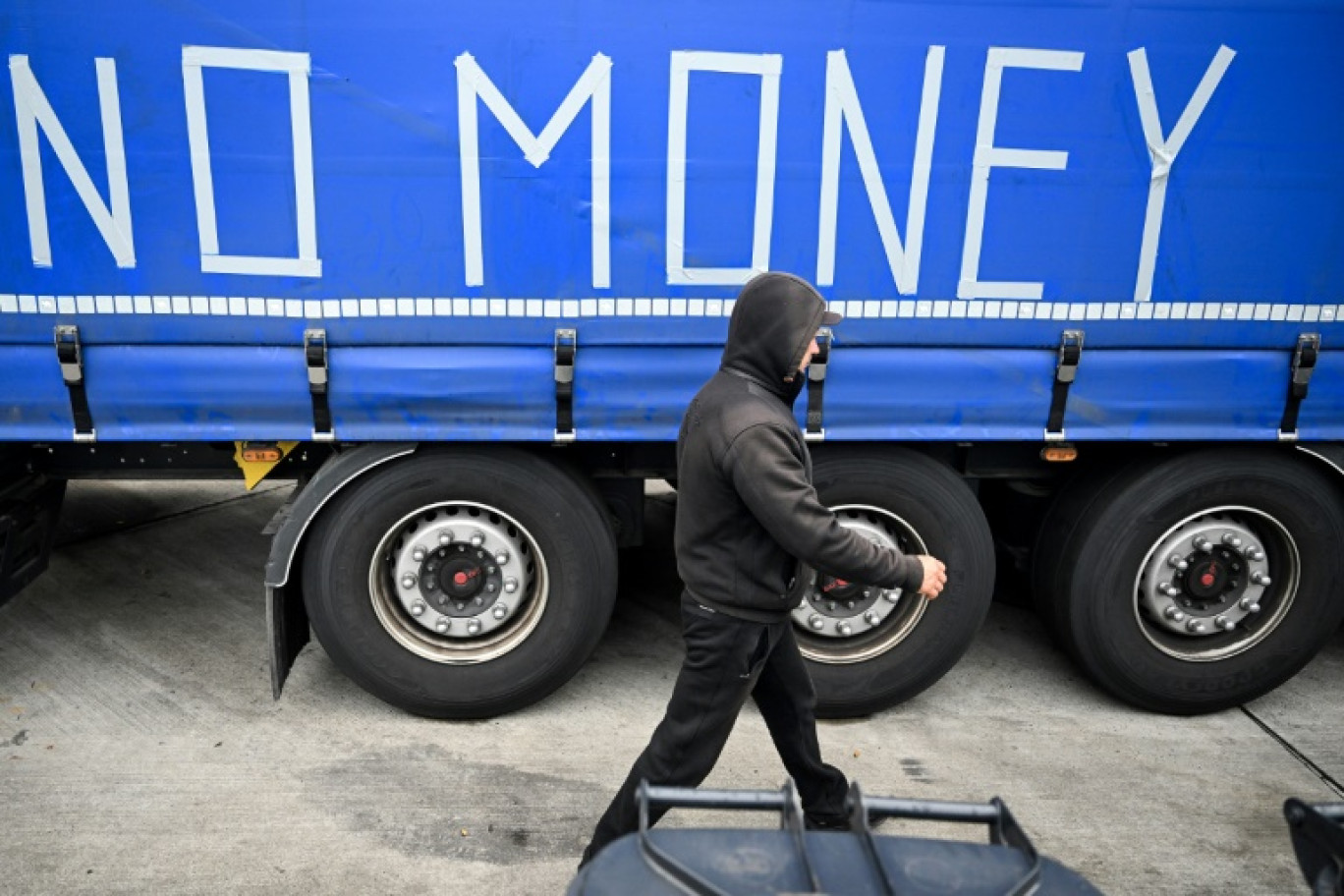 Un routier en grève marche devant un camion sur lequel est écrit "No Money" (pas d'argent) sur l'aire d'autoroute de Gräfenhausen, près de Francfort en Allemagne, le 22 septembre 2023 © Kirill KUDRYAVTSEV