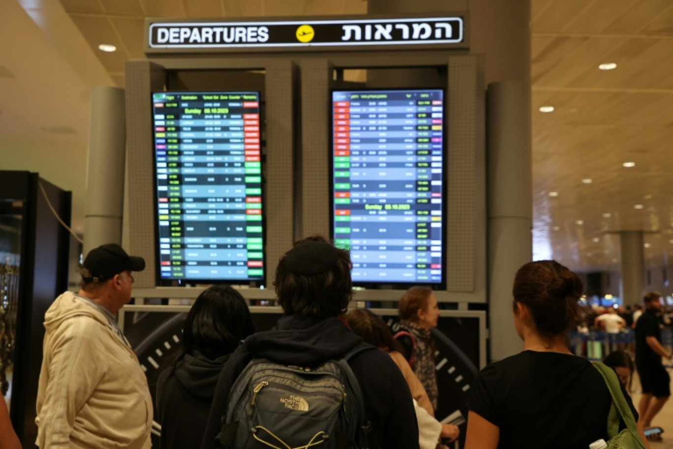 Des voyageurs consultent un tableau d'information sur les vols au départ de l'aéroport Ben Gourion, près de Tel-Aviv, le 7 octobre 2023 en Israël © GIL COHEN-MAGEN