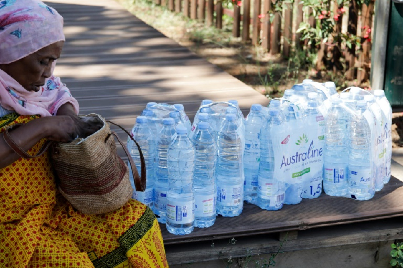 Une habitante assise à côté de packs de bouteilles d'eau reçus lors d'une distribution, le 21 septembre 2023 à Mayotte © Chafion MADI