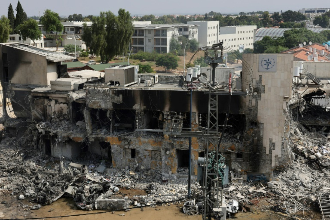 Des habitants tentent d'éteindre des véhicules en flammes au pied d'un immeuble résidentiel à Ashkelon, après des tirs de roquettes depuis la bande de Gaza vers Israël, le 7 octobre 2023 © AHMAD GHARABLI