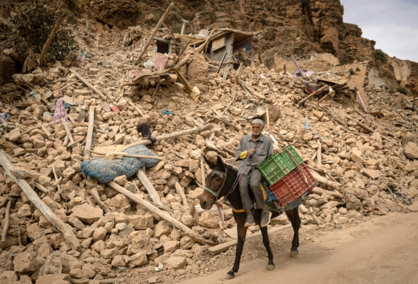 Un habitant passe à dos d'âne les décombres de bâtiments détruits par un séisme, le 5 octobre 2023 à Imi N'Tala, au Maroc © FADEL SENNA