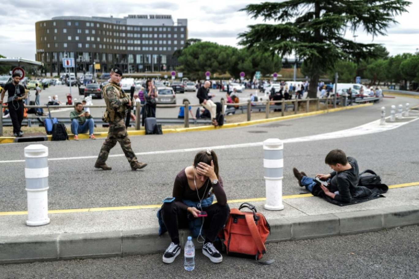 Des voyageurs attendent à l'extérieur de l'aéroport de Toulouse-Blagnac évacué après une alerte à la bombe, le 18 octobre 2023 © Charly TRIBALLEAU