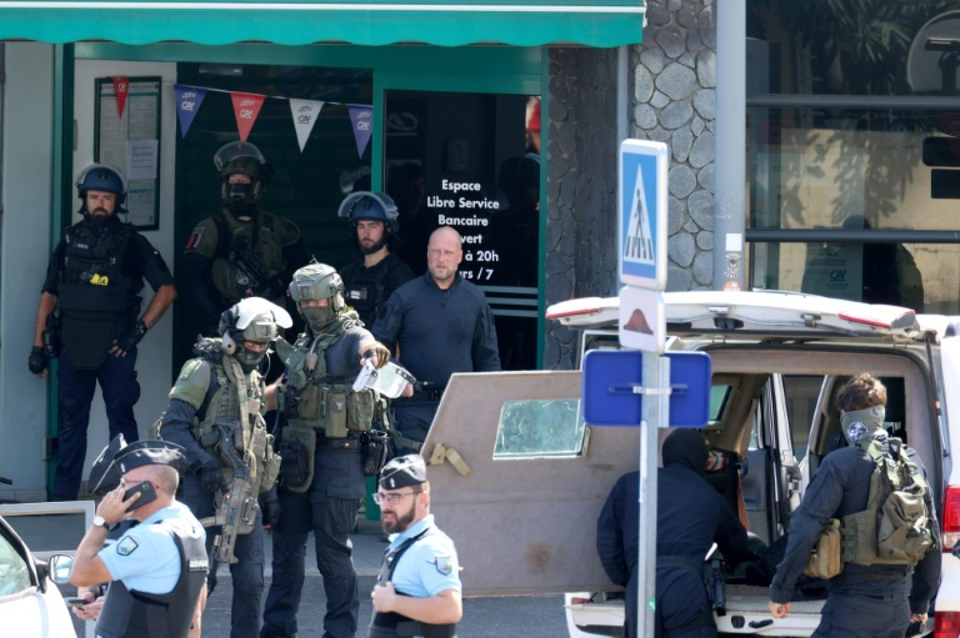 Des gendarmes et des membres de l'unité du Groupe d'intervention de la gendarmerie nationale (GIGN)  devant une agence bancaire où un homme est soupçonné d'avoir  mortellement frappé à l'arme blanche un agent d'entretien, le 28 octobre 2023 à La Possession, sur l'île de La Réunion © Richard BOUHET