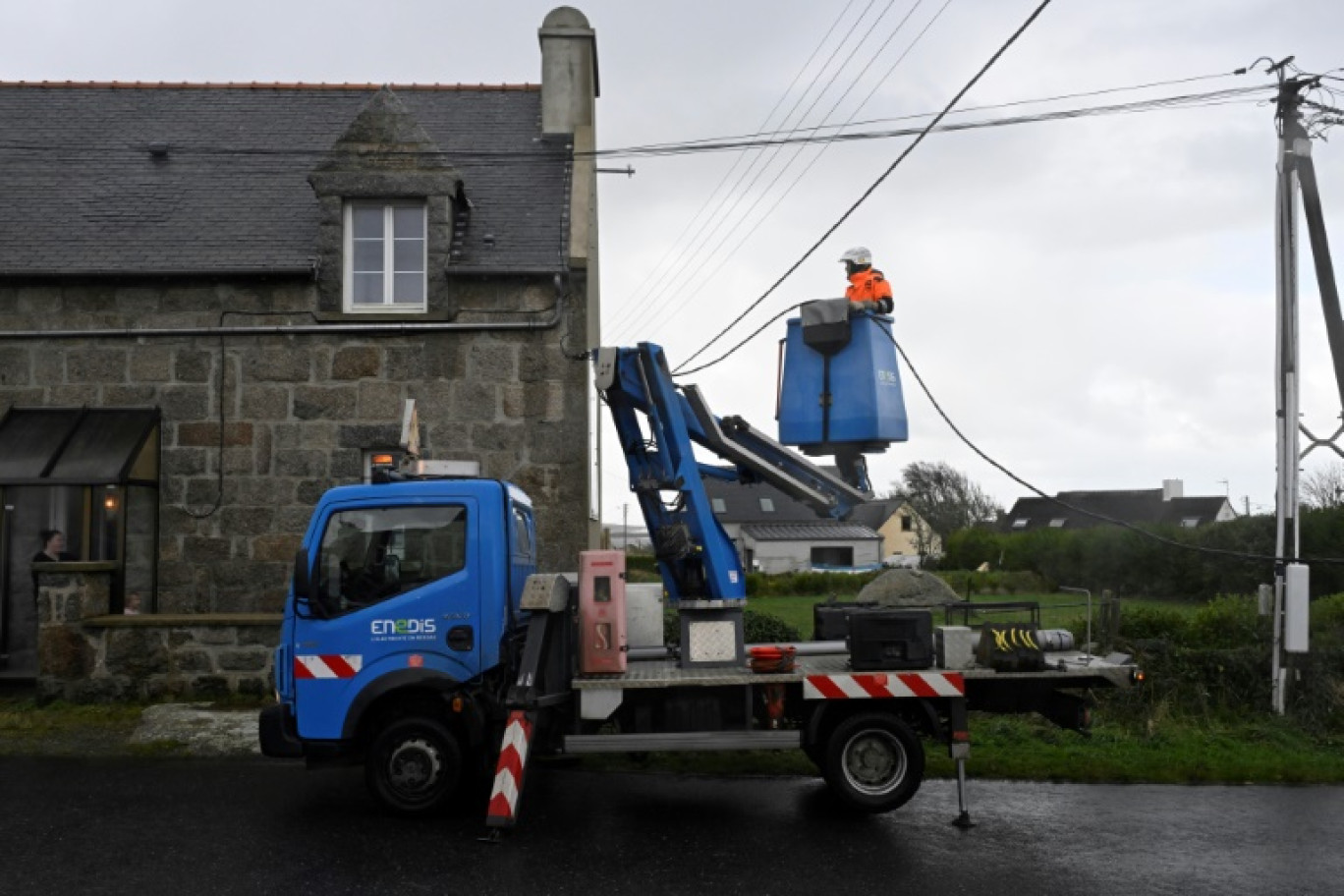 Un technicien d'Enedis raccorde des lignes électriques le 2 novembre 2023 à Lanildut, en Bretagne, après le passage de la tempête Ciaran © DAMIEN MEYER