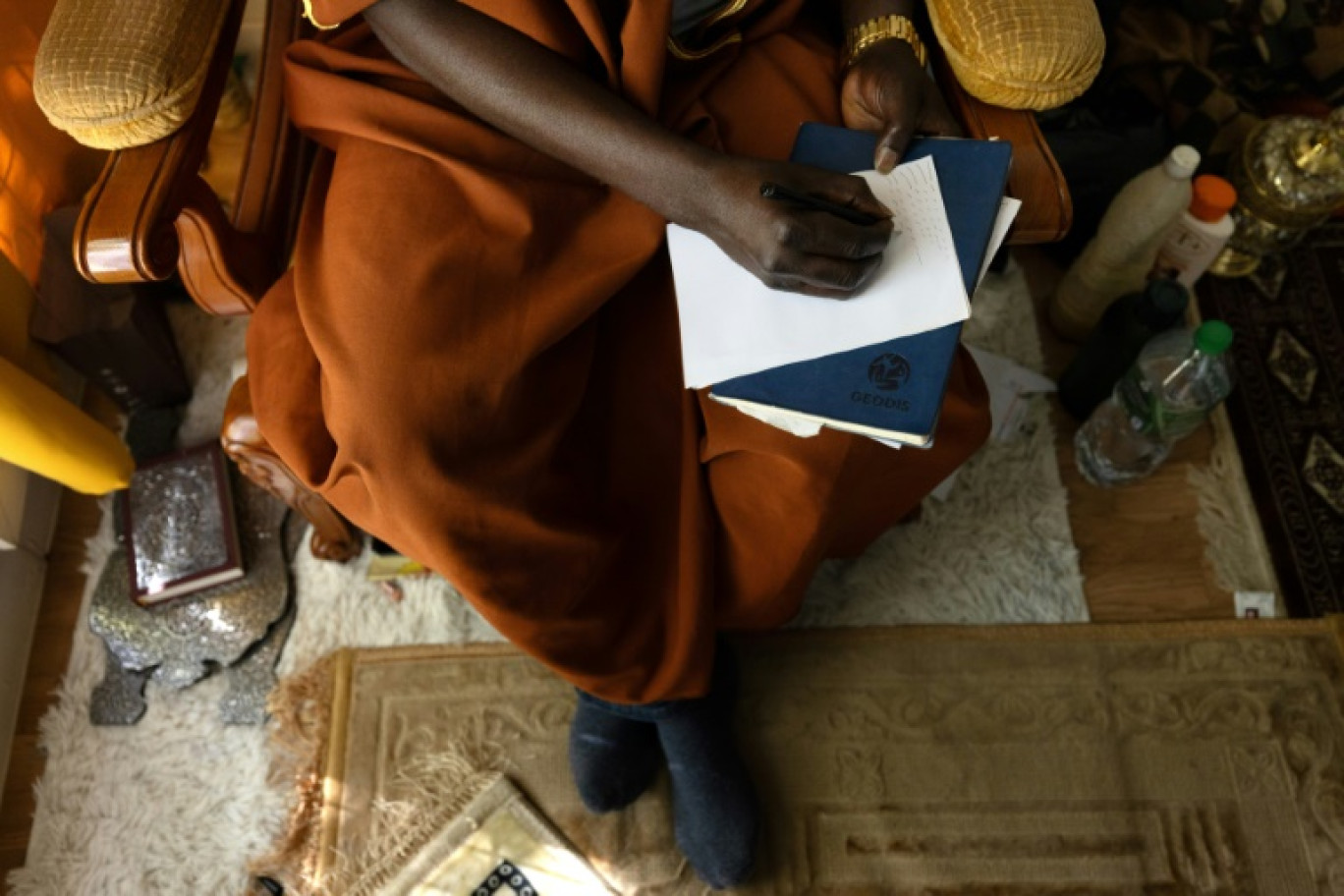 Le guérisseur africain Cheick Issa note en géomantique ce qu'il ressent lors de la consultation avec l'un de ses clients, le 16 septembre 2023 à Paris © JOEL SAGET