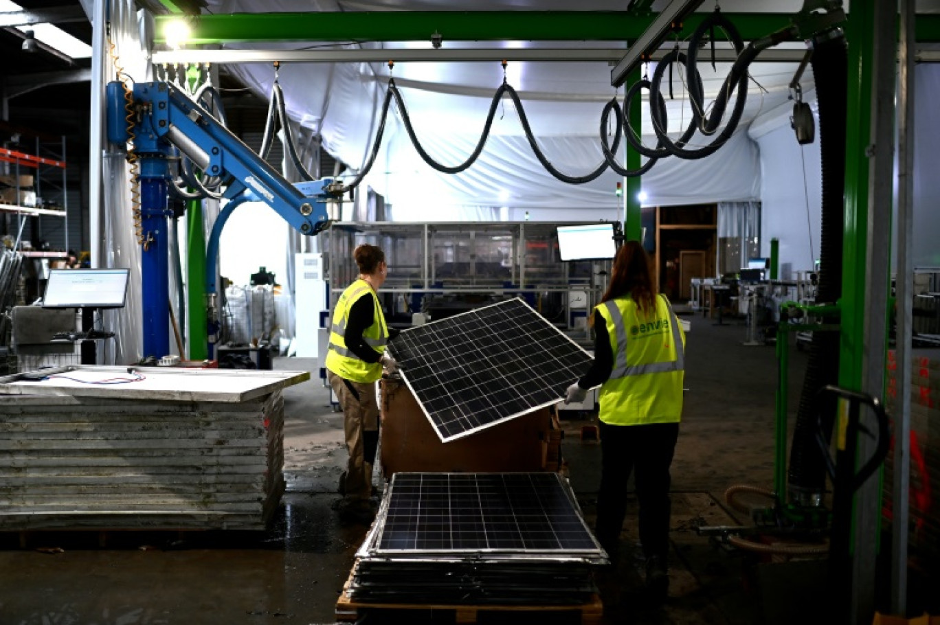 Des employées de l'entreprise Envie 2E passent dans une machine  un panneau solaire usagé pour le recyclage de ses pièces,  le 13 novembre 2023 à Saint-Loubès, en Gironde © Christophe ARCHAMBAULT