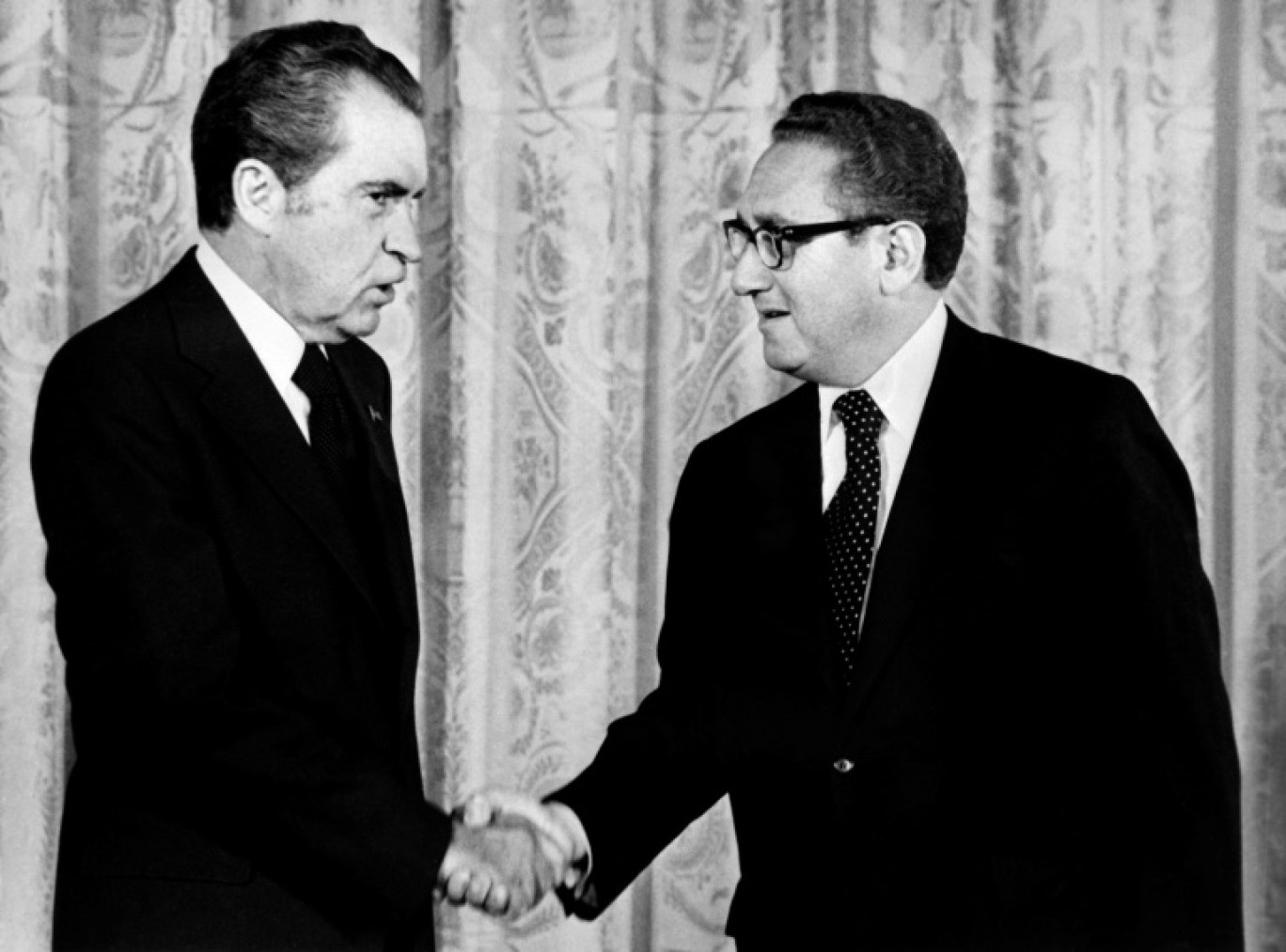 Le président américain Richard Nixon (G) serre la main d'Henry Kissinger, secrétaire d'Etat aux Affaires étrangères, en septembre 1973 à Washington © AFP FILES