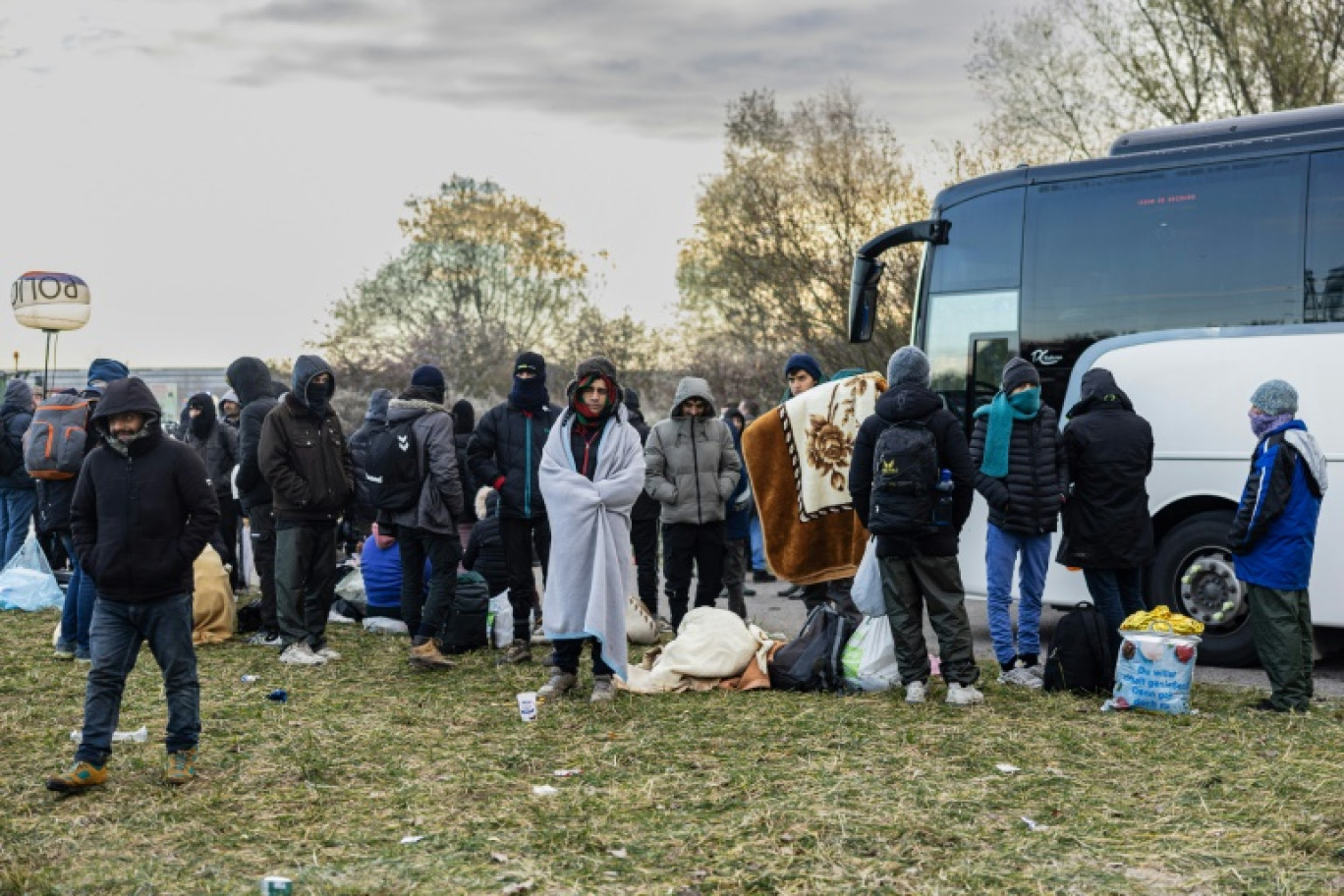 Des migrants attendent pour monter dans un autocar après l'évacuation de leur campement le 30 novembre 2023 à Loon-Plage, près de Dunkerque © Sameer Al-DOUMY