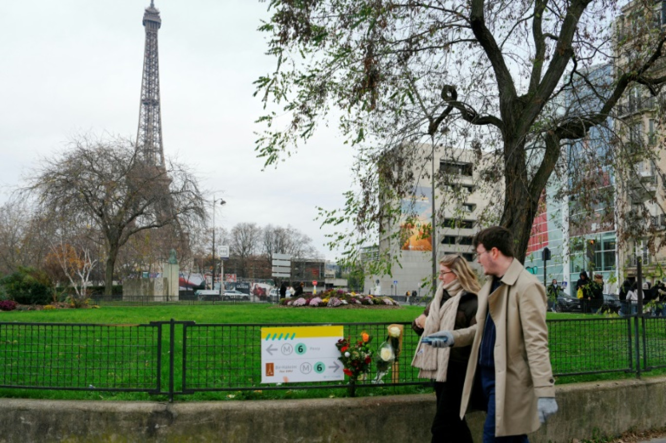 Deux personnes passent devant des fleurs déposées près de la tour Eiffel au lendemain de l'attaque au couteau d'un islamiste radical qui a tué un touriste et blessé deux autres personnes, le 3 décembre 2023 à Paris © Dimitar DILKOFF