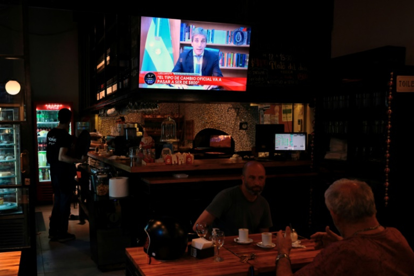 Le ministre argentin de l'Economie, Luis Caputo, à la télévision dans un bar de Buenos Aires lors de l'annonce des nouvelles mesures économiques du gouvernement du président Javier Milei, le 12 décembre 2023 © Luis ROBAYO