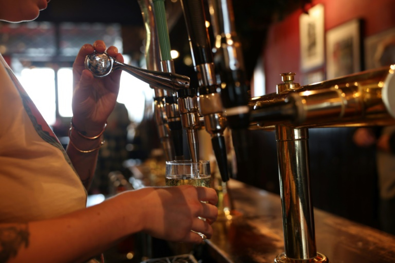 Une serveuse remplit une pinte de bière dans un pub à Limehouse, dans le sud de Londres, le 14 décembre 2023 © Daniel LEAL