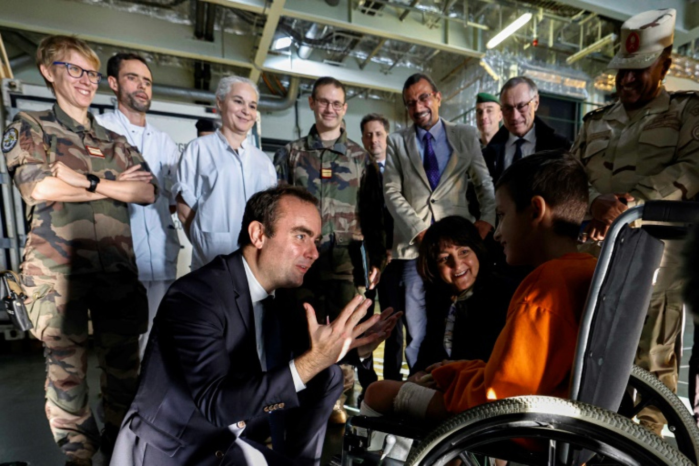 Le ministre des Armées Sebastien Lecornu s'entretient avec un enfant palestinien blessé à bord du Dixmude, le porte-hélicoptère français ancré dans le port égyptien d'Al-Arich, où sont soignés des civils blessés de Gaza, le 31 décembre 2023 © Khaled DESOUKI