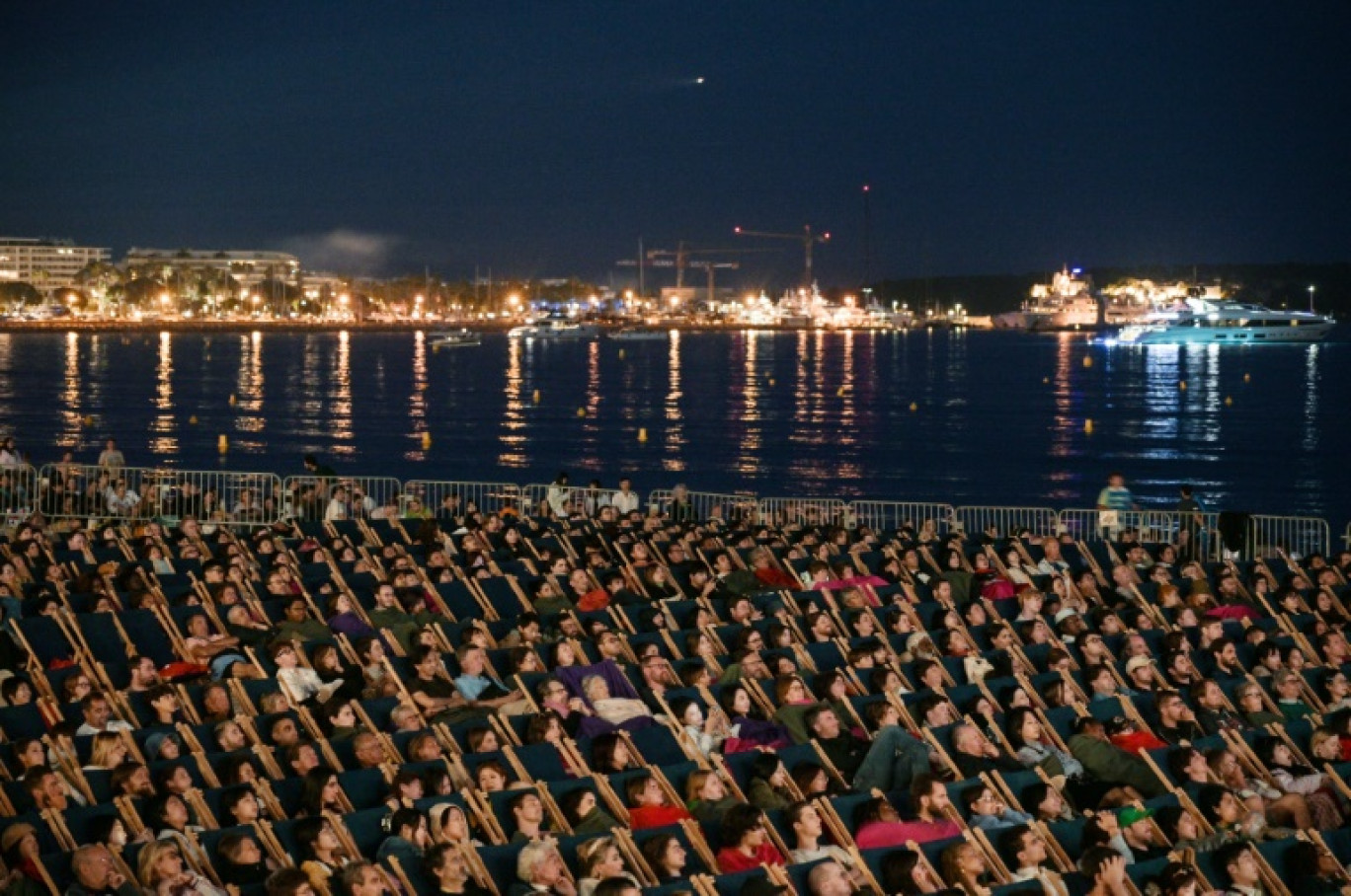 Des spectateurs assistent à une séance du "cinéma de la plage" en marge du 76e festival de Cannes le 26 mai 2023 © Stefano RELLANDINI