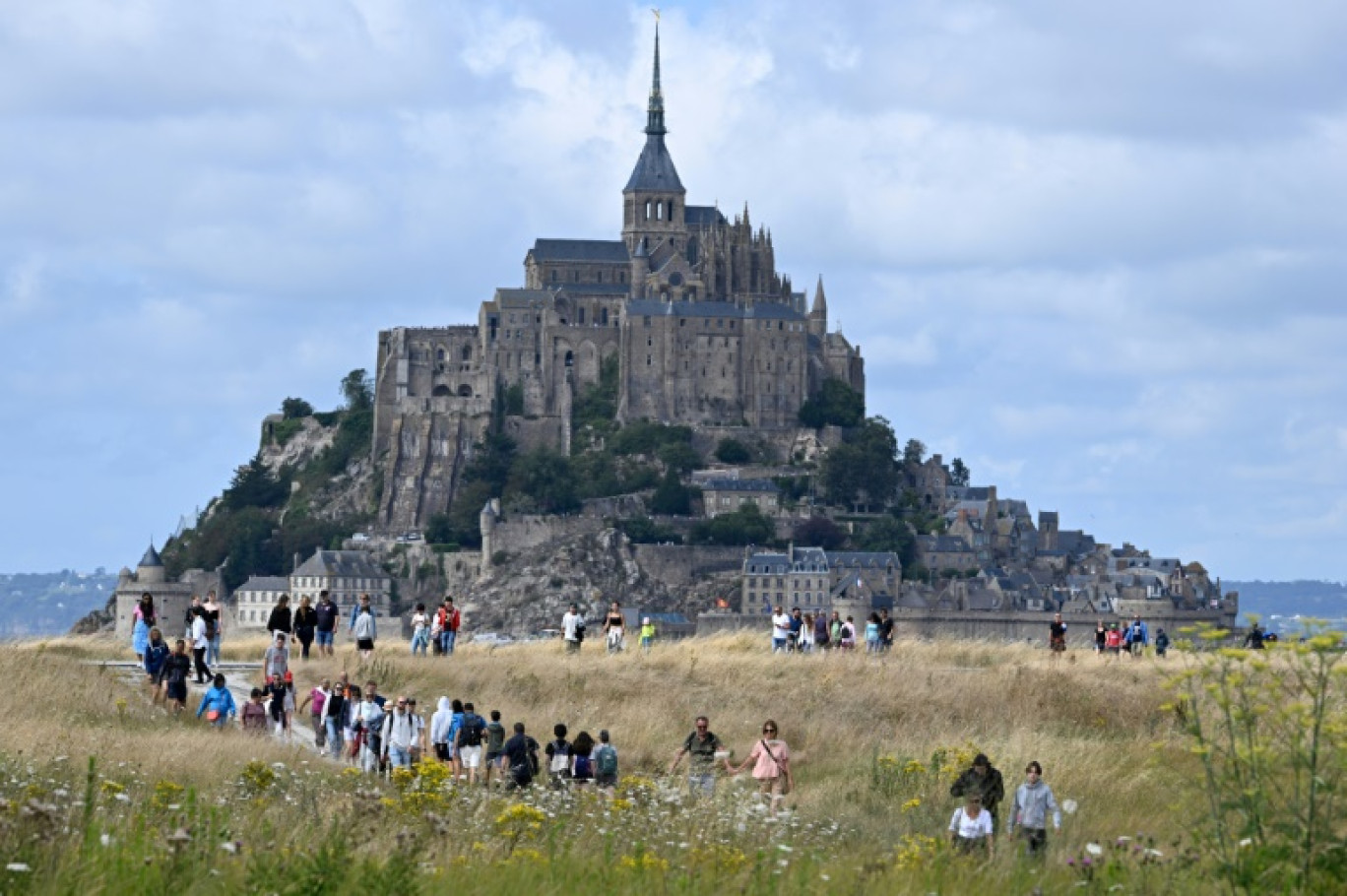 Des touristes marchent près du Mont-Saint-Michel, dans la Manche, le 25 juillet 2023 © Damien MEYER