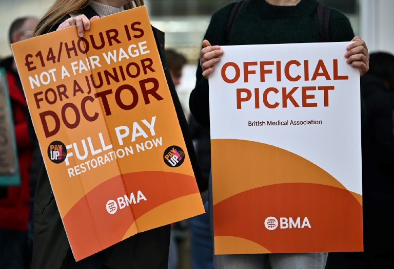 Des "juniors doctors" brandissent des pancartes réclamant de meilleurs salaraires du syndicat British Medical association lors d'un piquet de grève devant un hôpital de Londres le 20 décembre 2023 © Ben Stansall