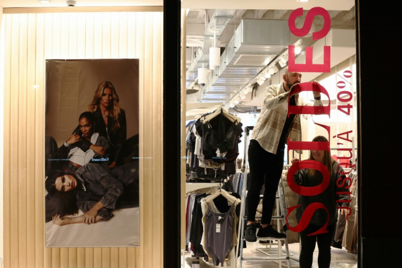 Des commerçants affichent une bannière annonçant les soldes d'hiver la veille de leur lancement le 9 janvier 2024 à Strasbourg © FREDERICK FLORIN