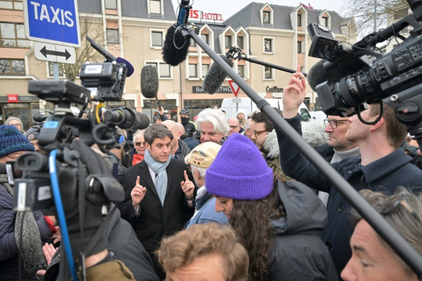 Le Premier ministre Gabriel Attal (c) parle avec des habitants sur le marché de Caen, le 14 janvier 2024 dans le Calvados © LOU BENOIST