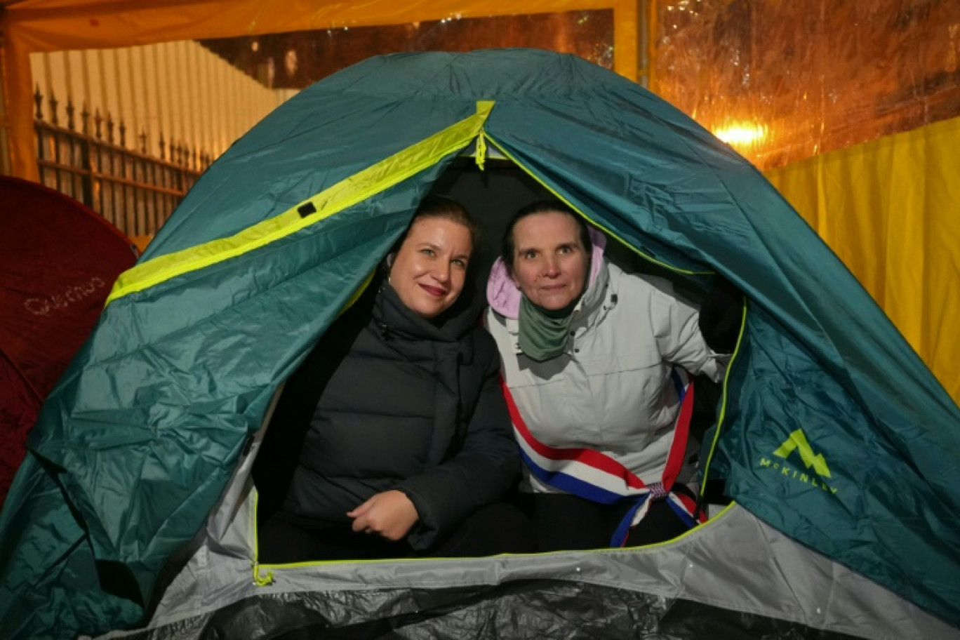 La cheffe des députés de La France insoumise Mathilde Panot (g) et sa collège députée Caroline Fiat, sous une tente, avant de passer une nuit dans la rue dans un campement mis en place par l'association française DAL pour des familles sans abri, le 16 janvier 2024 à Paris © Dimitar DILKOFF