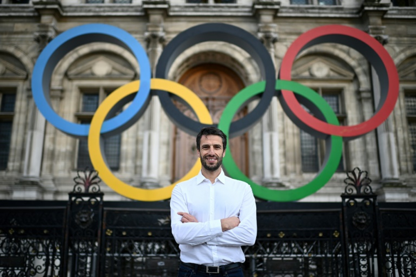 Le président du Comité d'organisation des Jeux Olympiques et Paralympiques de Paris 2024, Tony Estanguet, devant les anneaux olympiques exposés sur la façade de l'Hôtel de Ville de Paris, le 13 mars 2023 © Christophe ARCHAMBAULT