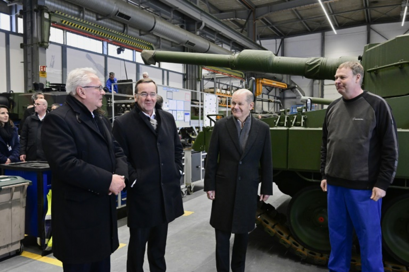 Armin Papperger, PDG du fabricant d'armes Rheinmetall, le ministre allemand de la Défense Boris Pistorius et le chancelier Olaf Scholz discutent avec un employé lors d'une visite d'une nouvelle usine d'armes à Unterluess, en Allemagne, le 12 février 2024 © FABIAN BIMMER