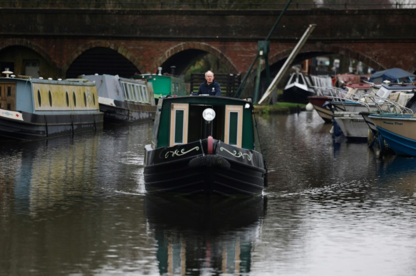 Neil Cocksedge, à bord de sa péniche hybirde "Eau de Folles", navigue sur un canal de plaisance d'Ashwood, le 25 janvier 2024 dans le centre de l'Angleterre © Daniel LEAL