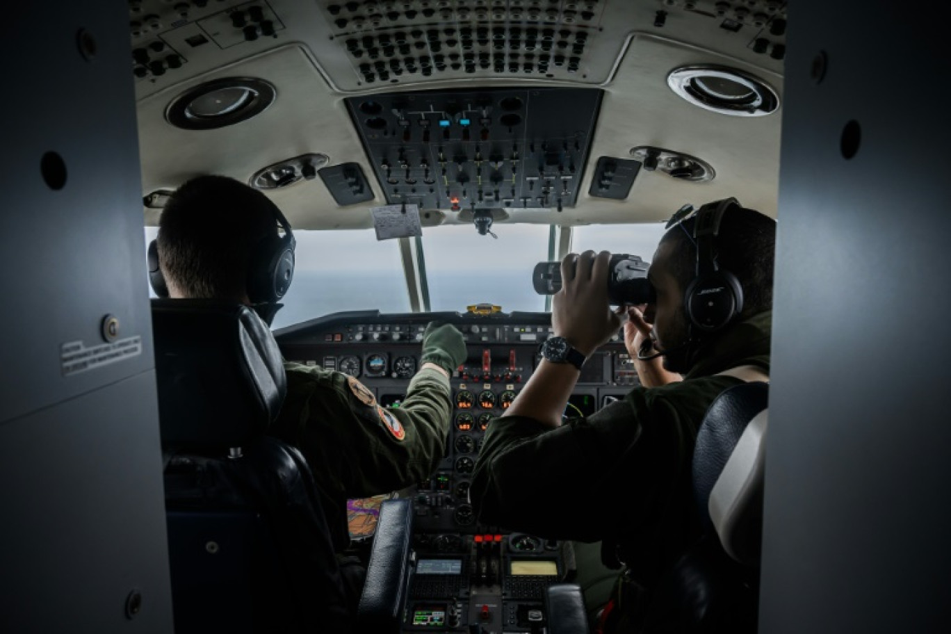 Un officier de la Marine Nationale de la flottille 24F surveille avec des jumelles les bateaux de pêche naviguant dans le golfe de Gascogne depuis un avion Falcon 50, le 5 février 2024 © LOIC VENANCE