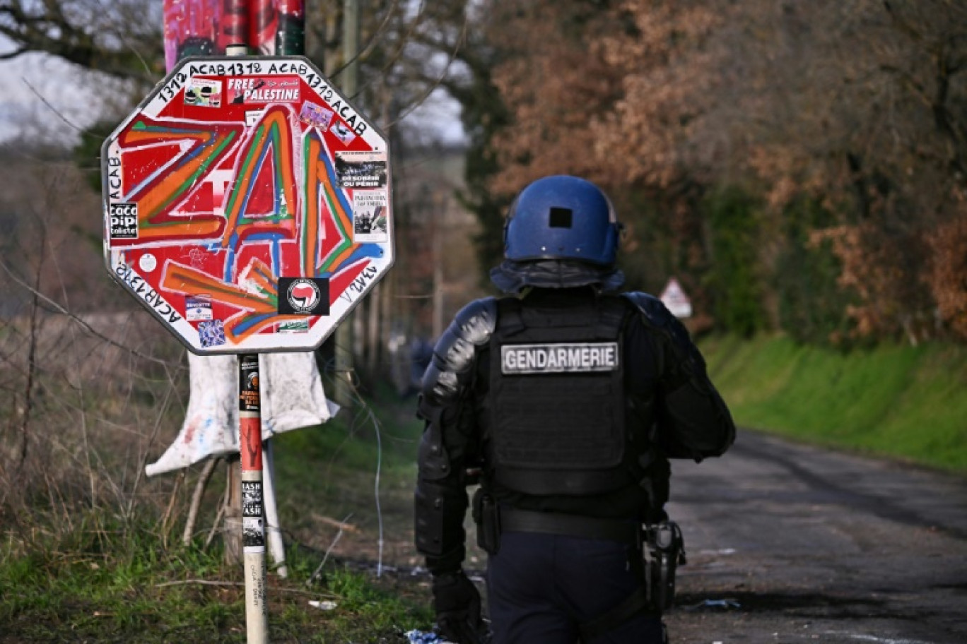 Un gendarme à côté d'un panneau "ZAD" lors d'une opération près d'un camp d'opposants à la contruction de l'A69 à Saïx, dans le Tarn, le 9 février 2024 © Lionel BONAVENTURE