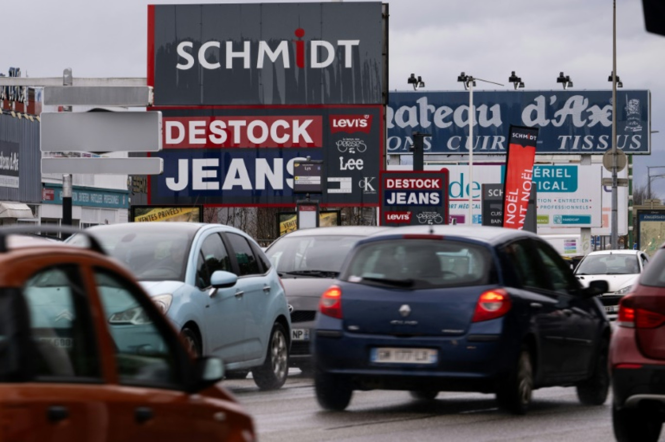 Cette photographie prise le 12 décembre 2023 montre des voitures passant devant des panneaux publicitaires dans la zone commerciale à Wittenheim © SEBASTIEN BOZON