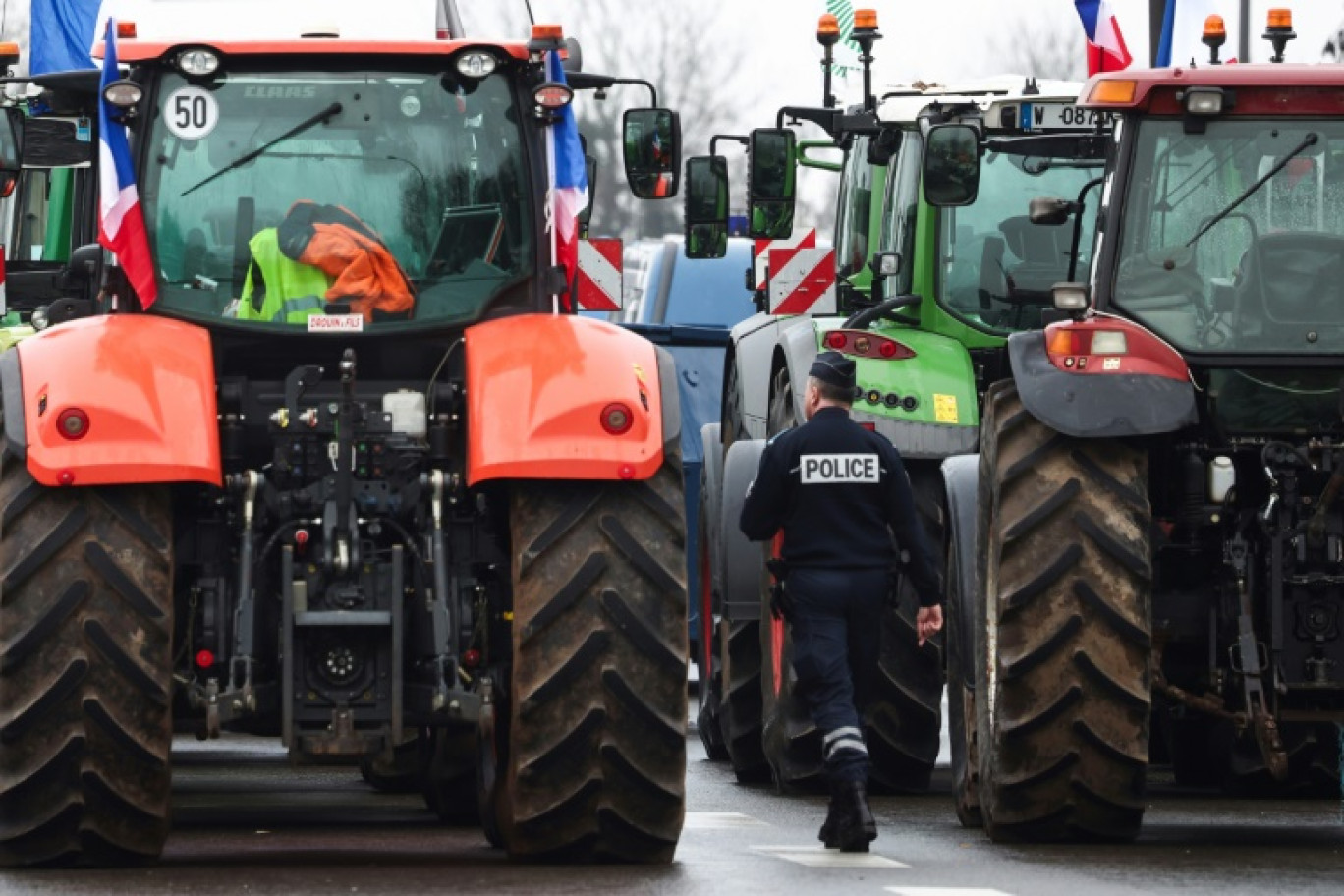 Un policier marche près de tracteurs bloquant l'autoroute A6, le 1er février 2024 près de Chilly-Mazarin en Essonne © EMMANUEL DUNAND