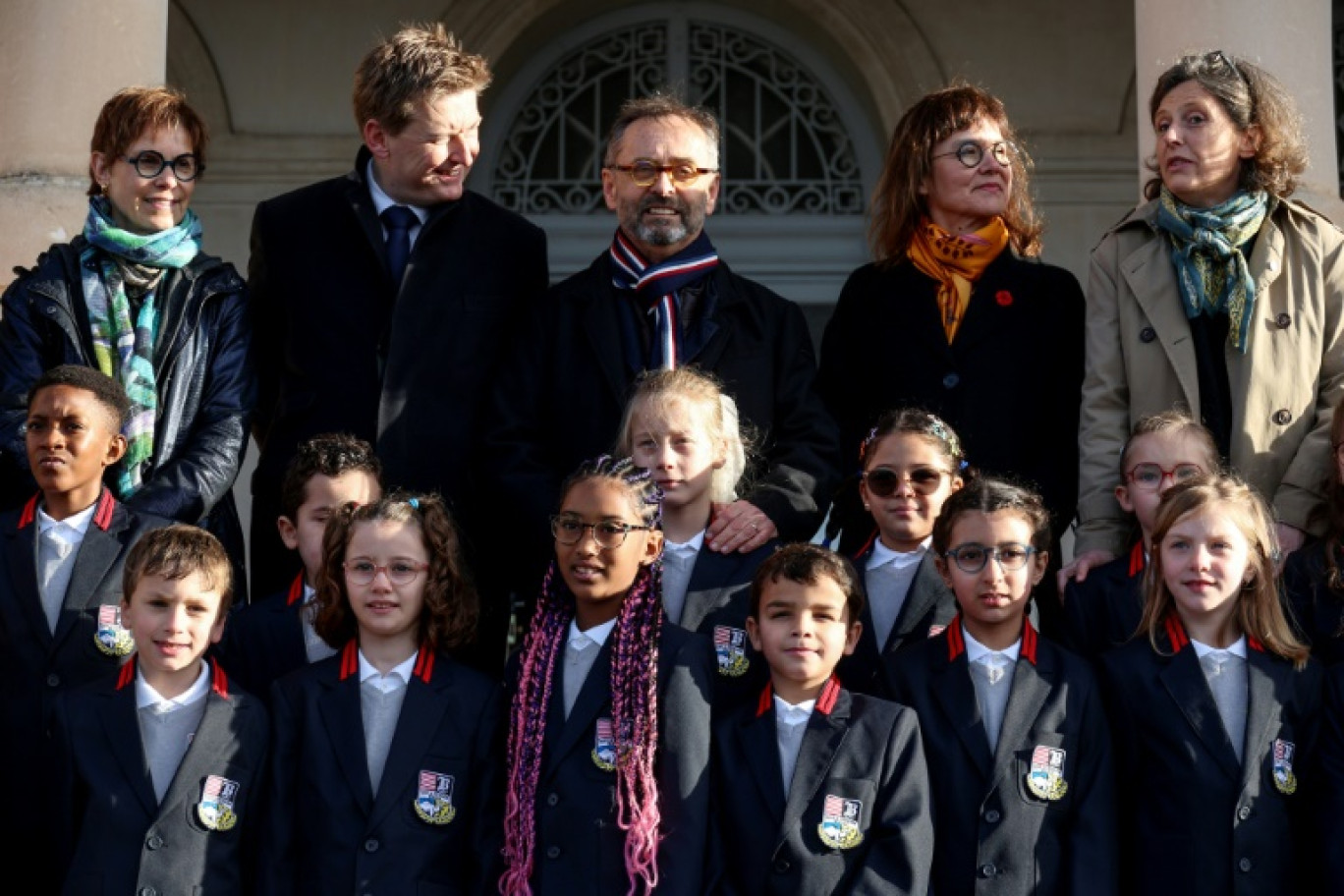 Le maire de Béziers, Robert Ménard (au centre), à côté d'élèves en uniforme dans la cour de l'école primaire du Château de la Chevaliere à Béziers, le 26 février 2024 © Pascal GUYOT