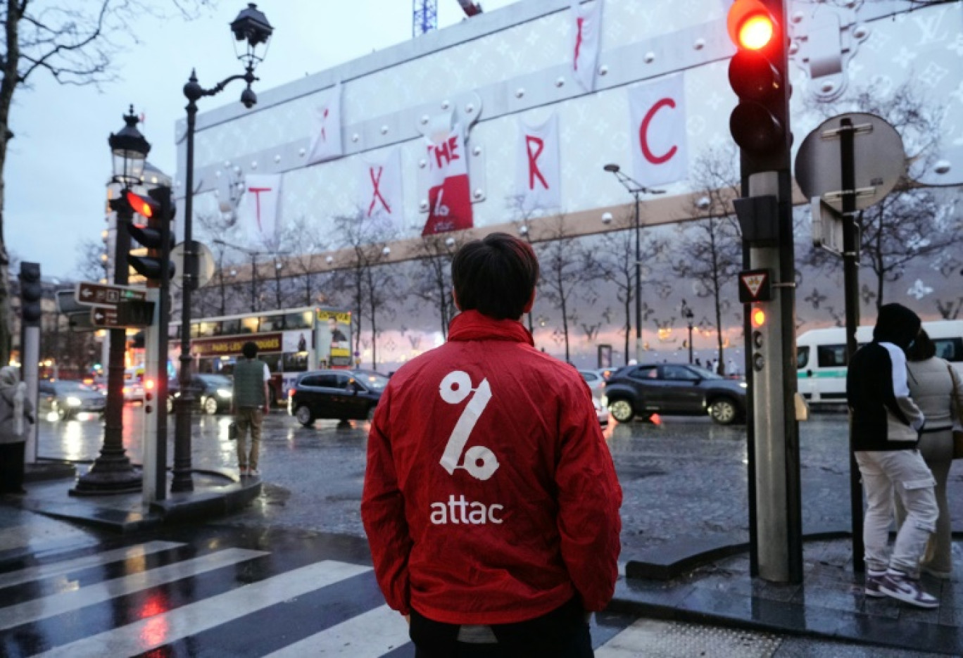 Un activiste d'Attac devant la banderole déployée sur la façade du futur hôtel Vuitton à Paris, le 24 février 2024 © Dimitar DILKOFF