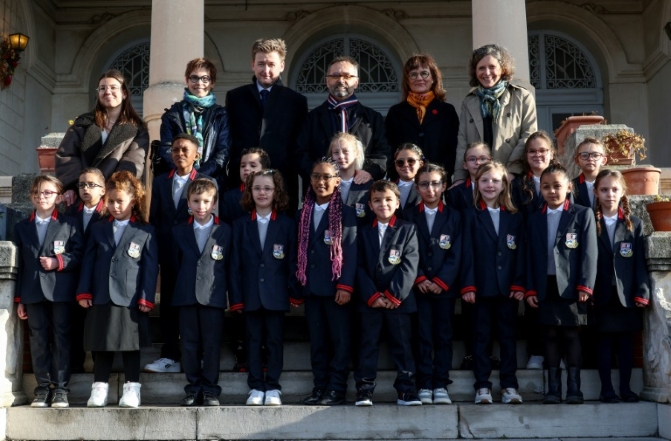 Le maire de Béziers, Robert Ménard (au centre), à côté d'élèves en uniforme dans la cour de l'école primaire du Château de la Chevaliere à Béziers, le 26 février 2024 © Pascal GUYOT